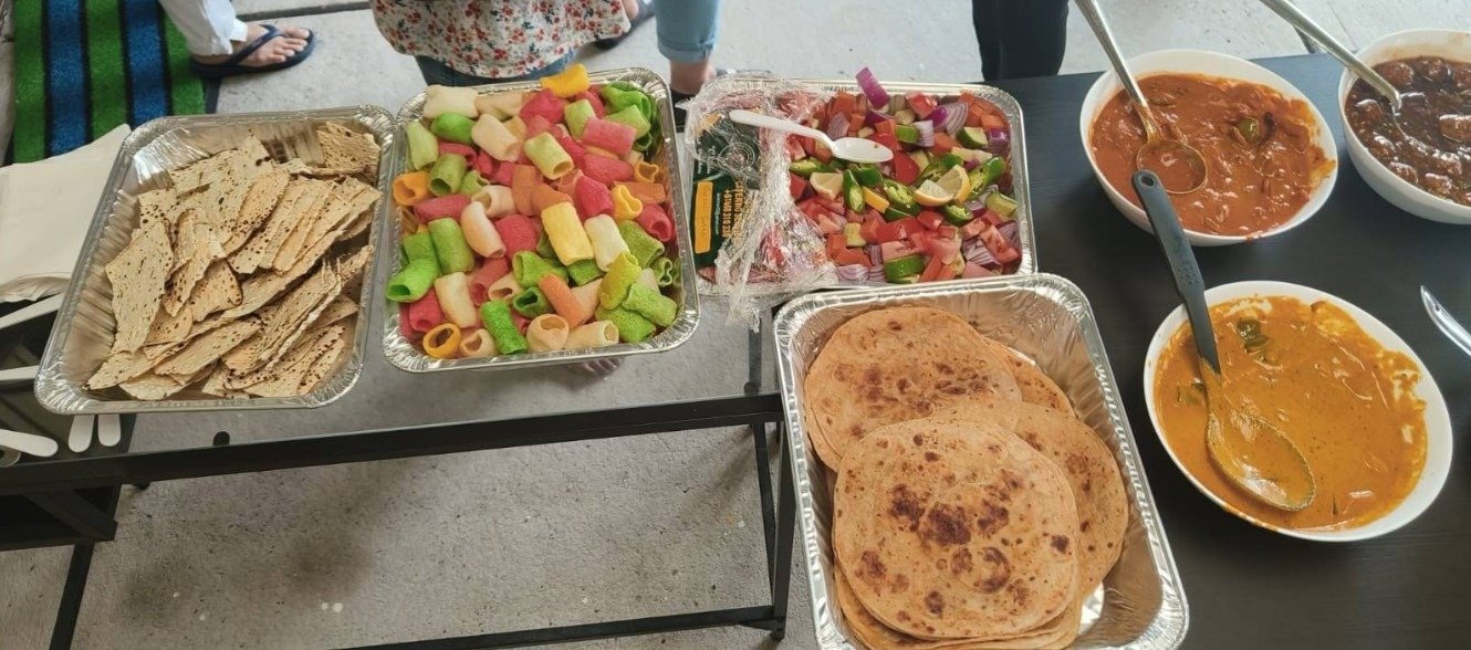 K Kitchen Schofields foil catering trays of parathas, salad and curries laid out for a party