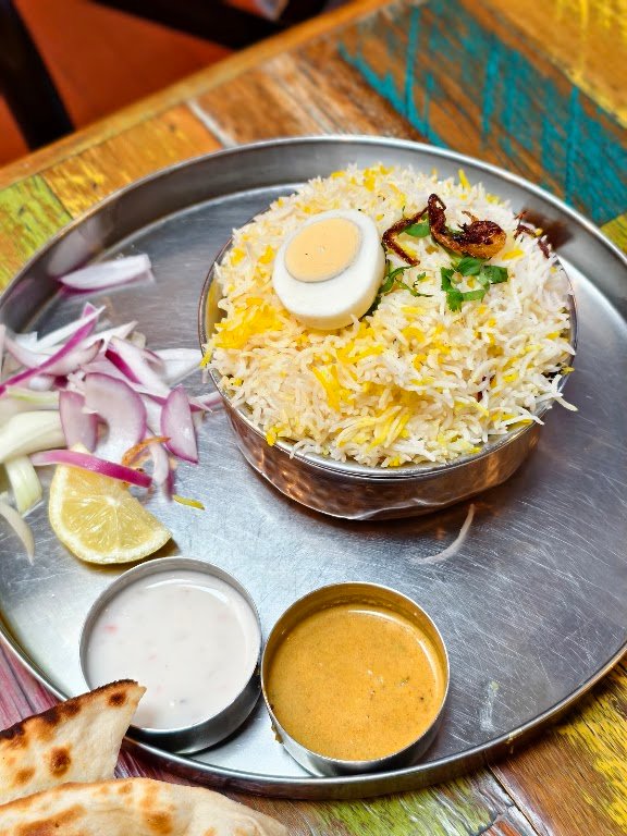 IndoChainese biryani plate with boiled egg and raita
